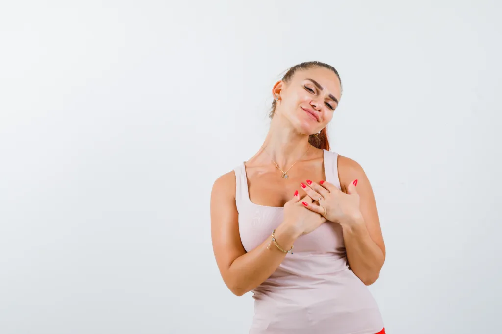 Young woman confidently holding her hands on her clear, healthy chest, symbolizing effective skincare and clogged pore prevention.