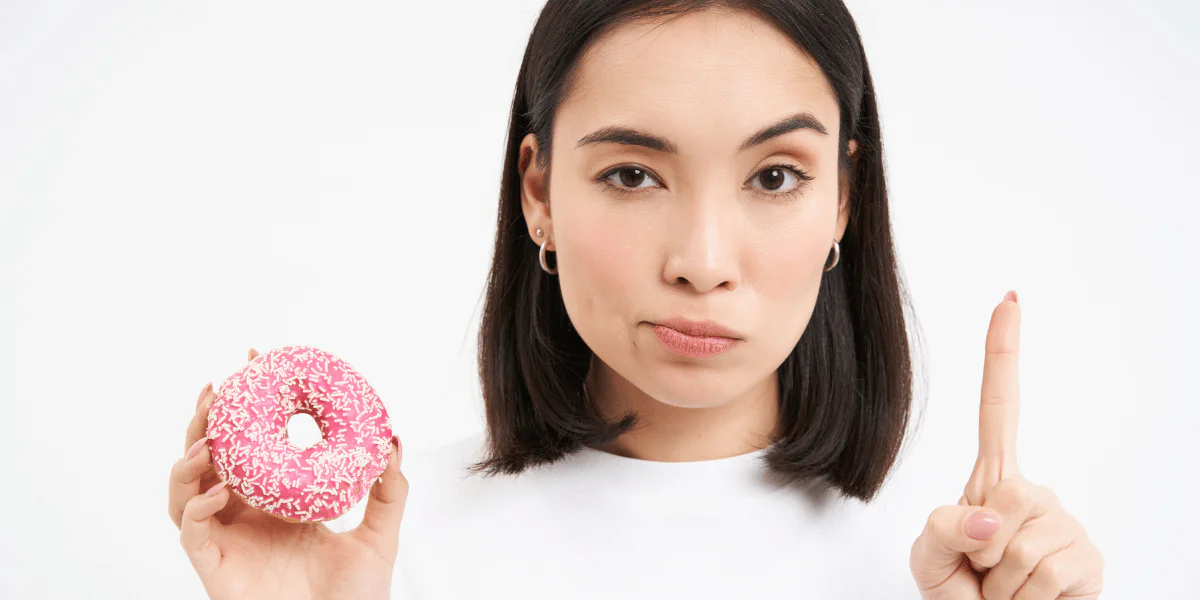 Woman rejecting doughnut to avoid sugar